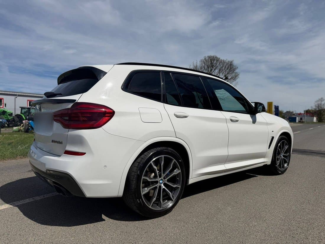 Bílé BMW X3 zezadu z boku na parkovišti